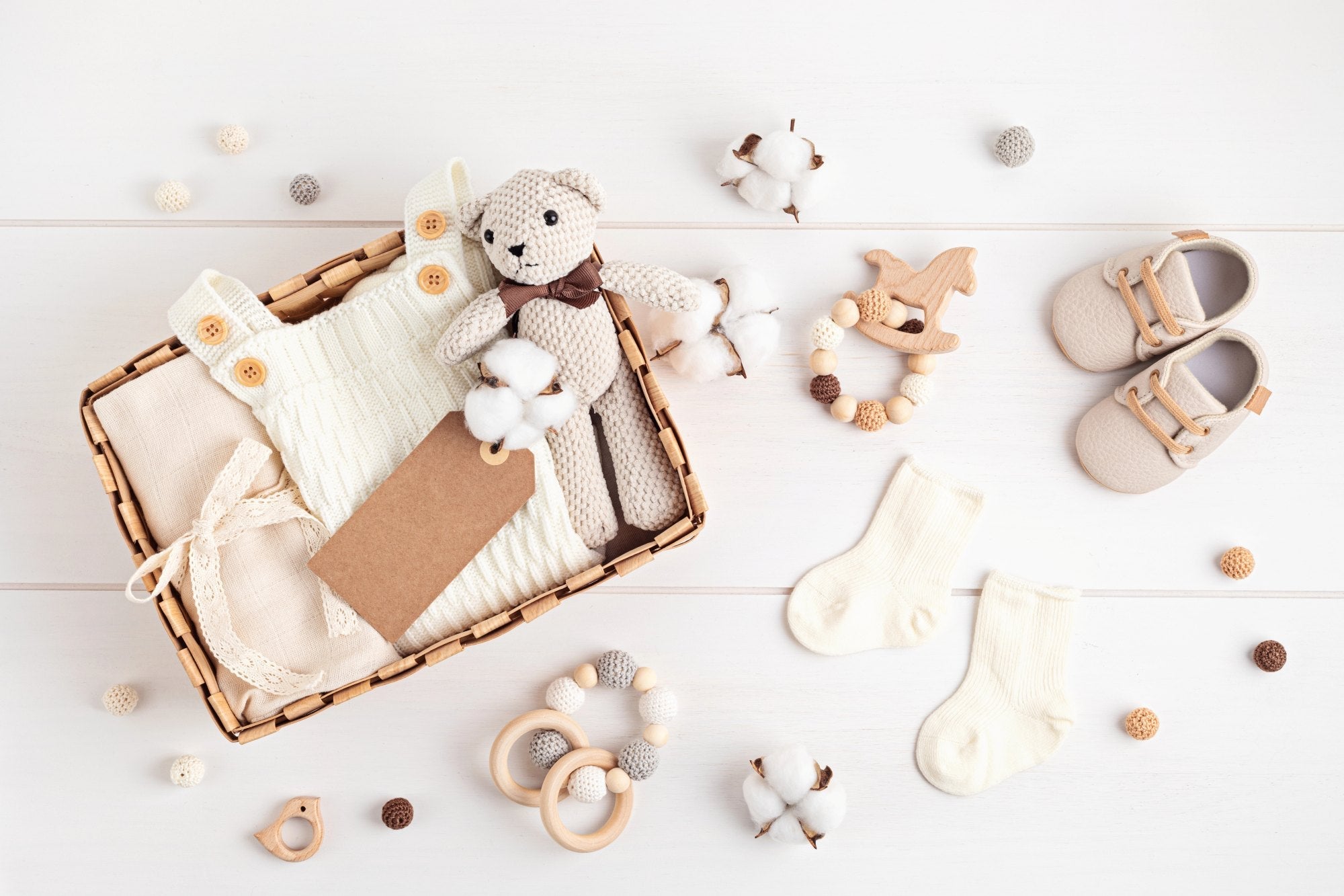 an aerial photo of neutral baby items in a wicker basket