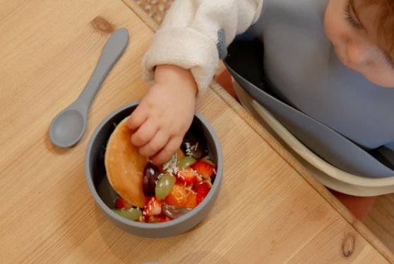 a small child eating from silicone dinnerware using their hands