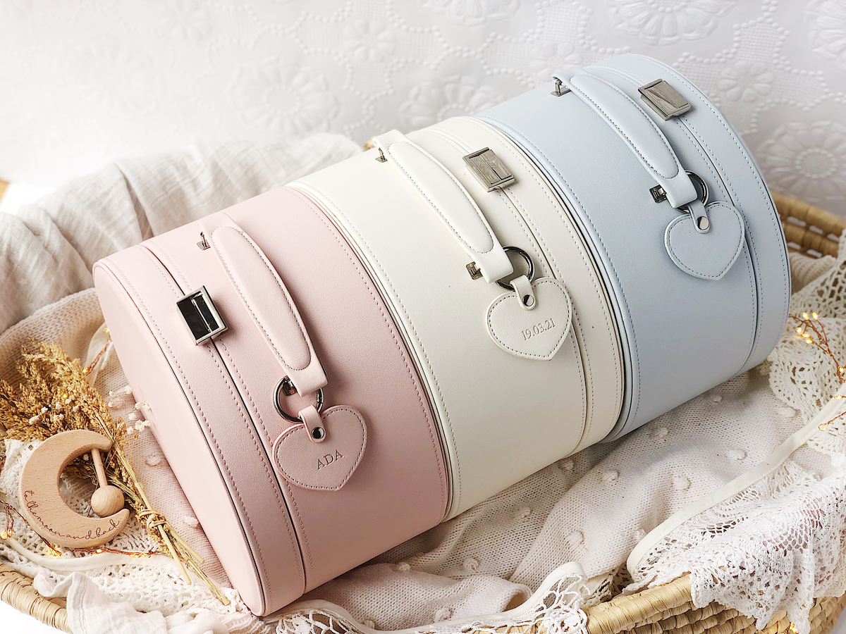 Baby Keepsake Boxes in three different colours of cream, pink and grey stacked neatly together on a cream baby blanket