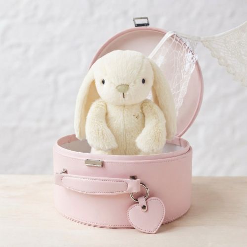 A cream-colored plush bunny toy sitting inside an open keepsake box with a lace veil, placed on a light wooden surface against a white textured wall.