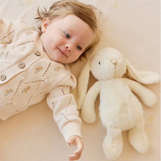 cream plush bunny laying next to baby