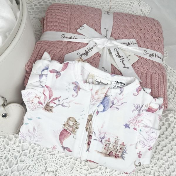 Set of baby blankets and clothing with 'Snuggle Hunny' branding on a textured surface.