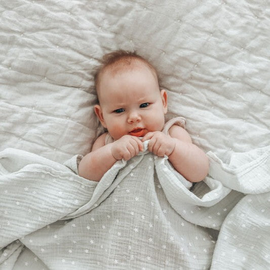 Baby lying on a textured blanket with a soft focus