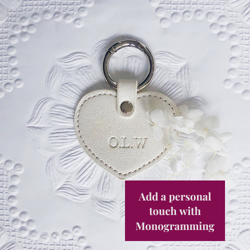Heart-shaped keychain with 'O.L.W.' monogram on a textured white background