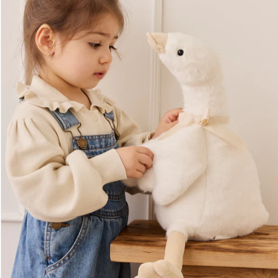 Child playing with a plush toy duck on a wooden surface