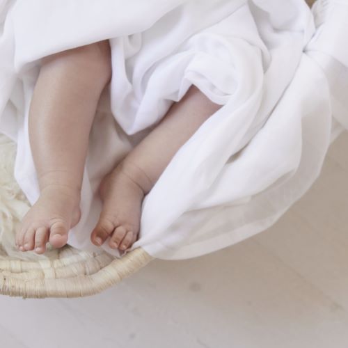 baby feet surrounded by muslin wrap in a Moses basket