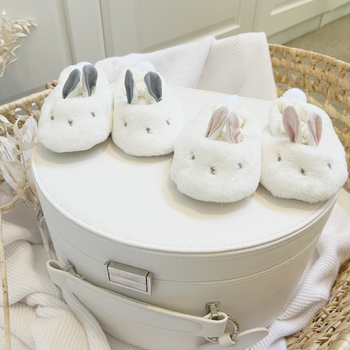 two pairs of fluffy bunny slippers on top of a cream keepsake box