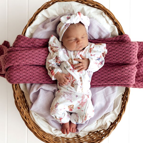 Newborn baby in a basket with pink blanket and white headband