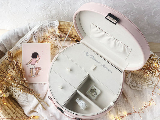 open keepsake box from above with compartment tray inside showing trinkets in the tray. The box is surrounded by fairy lights in a Moses basket