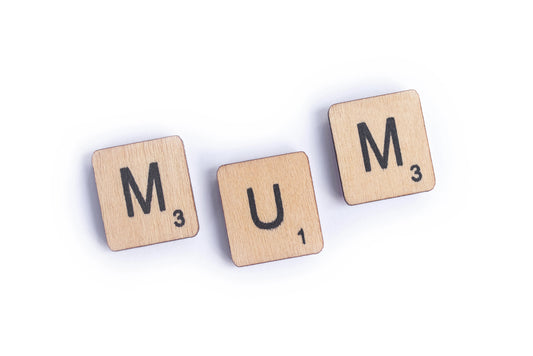 three scrabble tiles spelling out MUM on a white background