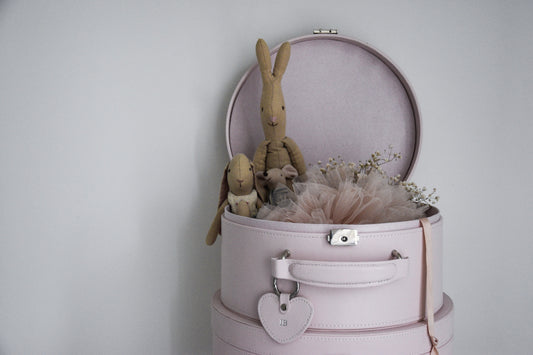 a stack of pink keepsake boxes with the top one open and contains a small bunny toy and pink tutu