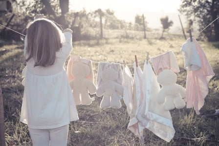 small child hanging toys on a clothes line