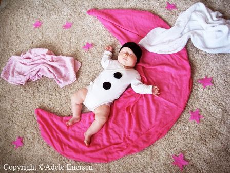 baby asleep on their back laying on a pink moon shaped blanket