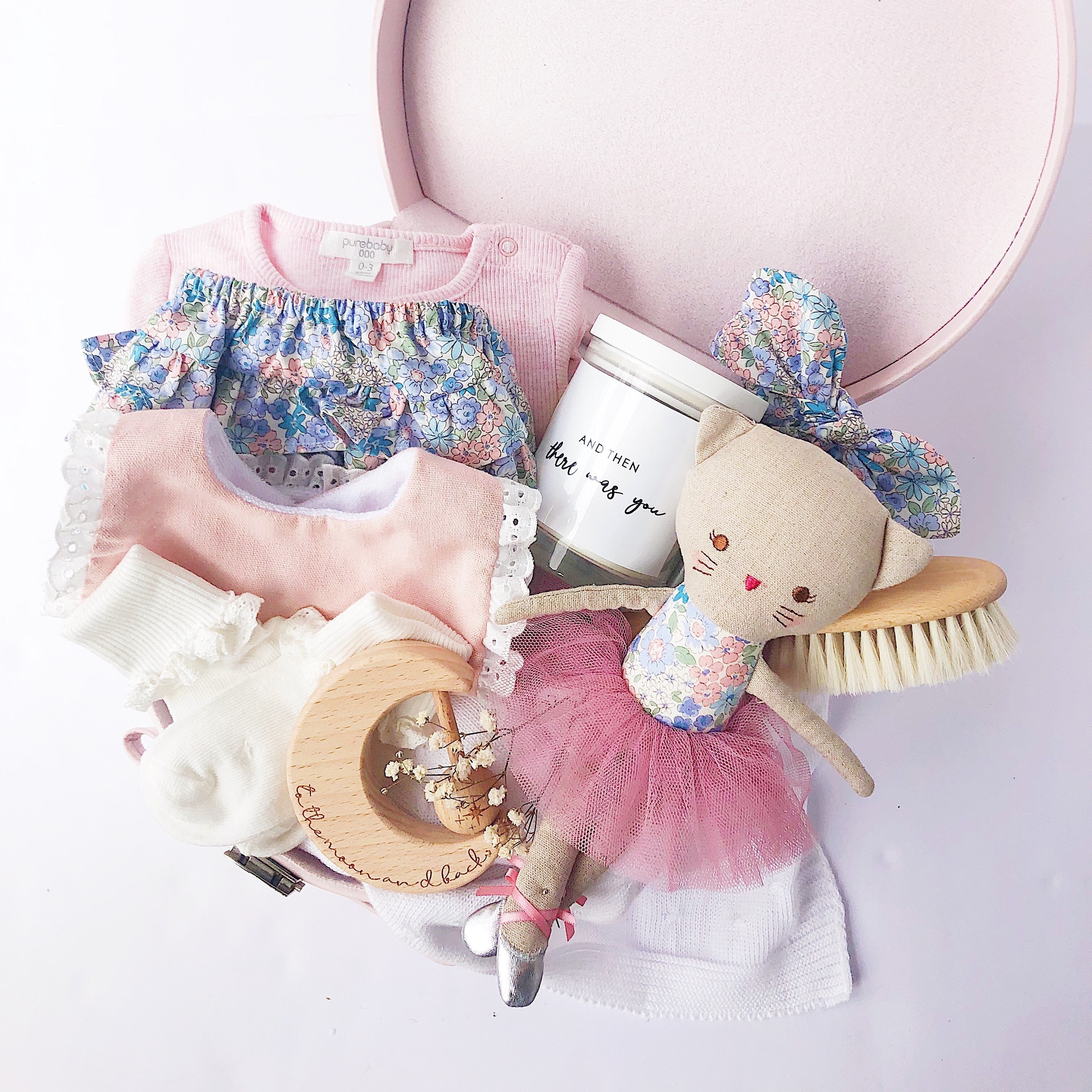 baby gift hamper in a pink keepsake box filled with baby items like a timber teether, kitty toy and baby clothing
