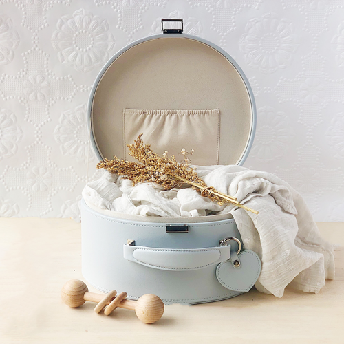 Grey keepsake box open with a cream coloured baby blanket inside and a timber rattle next to