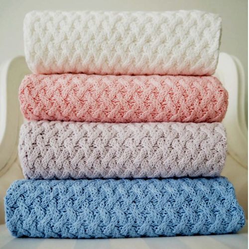 Stack of four crocheted blankets in white, pink, gray, and blue.