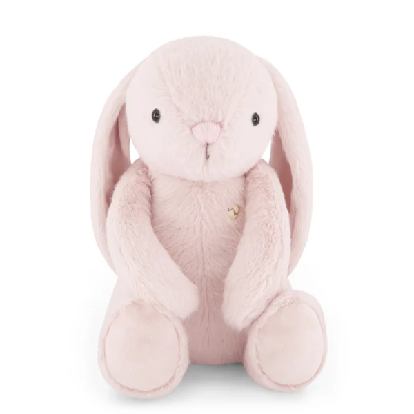 A light pink plush bunny toy with long floppy ears, black bead eyes, a small pink stitched nose, and a tiny gold heart on its chest, photographed on a clean white background.