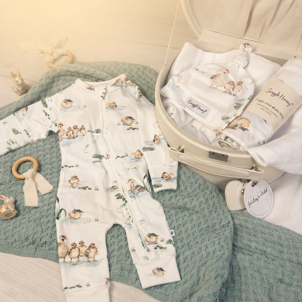 open keepsake box with baby onesie, beanie and wrap with duck pond print on sage blanket and neutral background