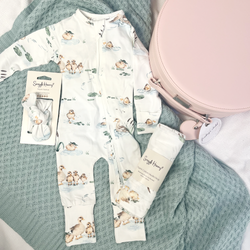 flat lay of duck pond print onesie, wrap and headband next to a pink keepsake box