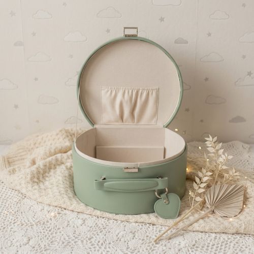 Green keepsake box with open lid on a textured surface with decorative elements.