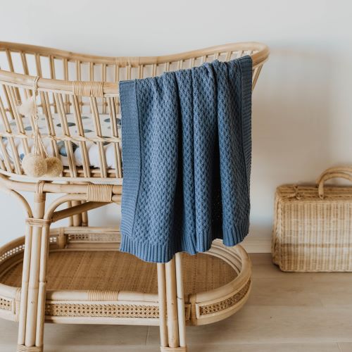 river blue baby blanket hanging over the edge of a timber baby bassinet