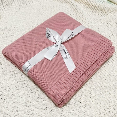blush baby blanket on textured cream background