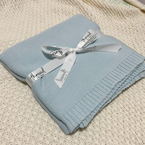 ice blue baby blanket on textured cream background