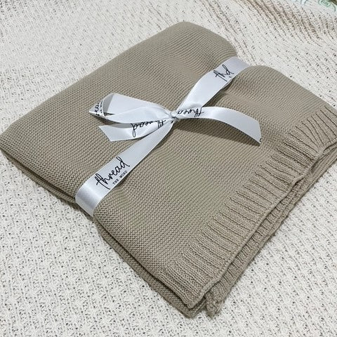 oat baby blanket on textured cream background