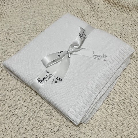 white baby blanket on textured cream background