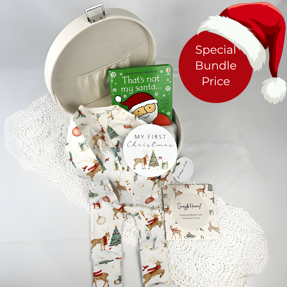 Baby outfit with Santa hat and 'My First Christmas' book on a white surface