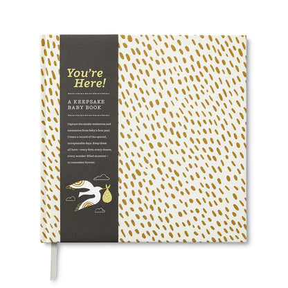 A keepsake baby journal. Cloth bound, hardcover with a white cover with gold flecks