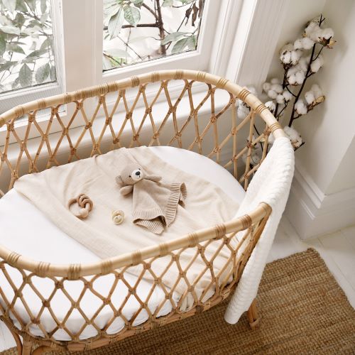 knitted bear comforter styled in cane cot by a window