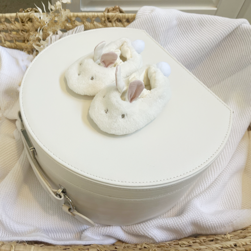 fluffy bunny slippers with pink ears on top of cream keepsake box