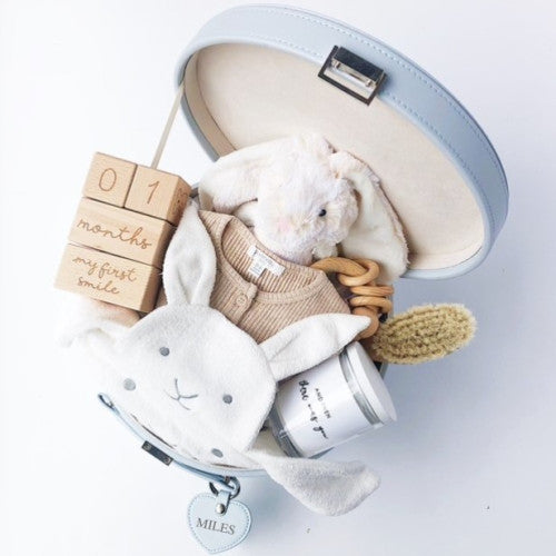 Keepsake box open showing a toy bunny, timber blocks, candle, baby hair brush and a bunny wash mitt inside