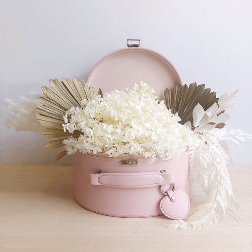 pink keepsake box with the lid open and an arrangement of flowers styled within in it