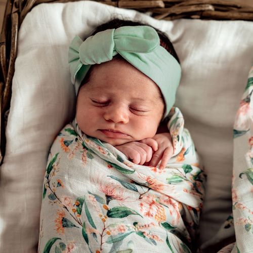 sleeping aby wrapped in a  swaddle wearing a sage knotted headband