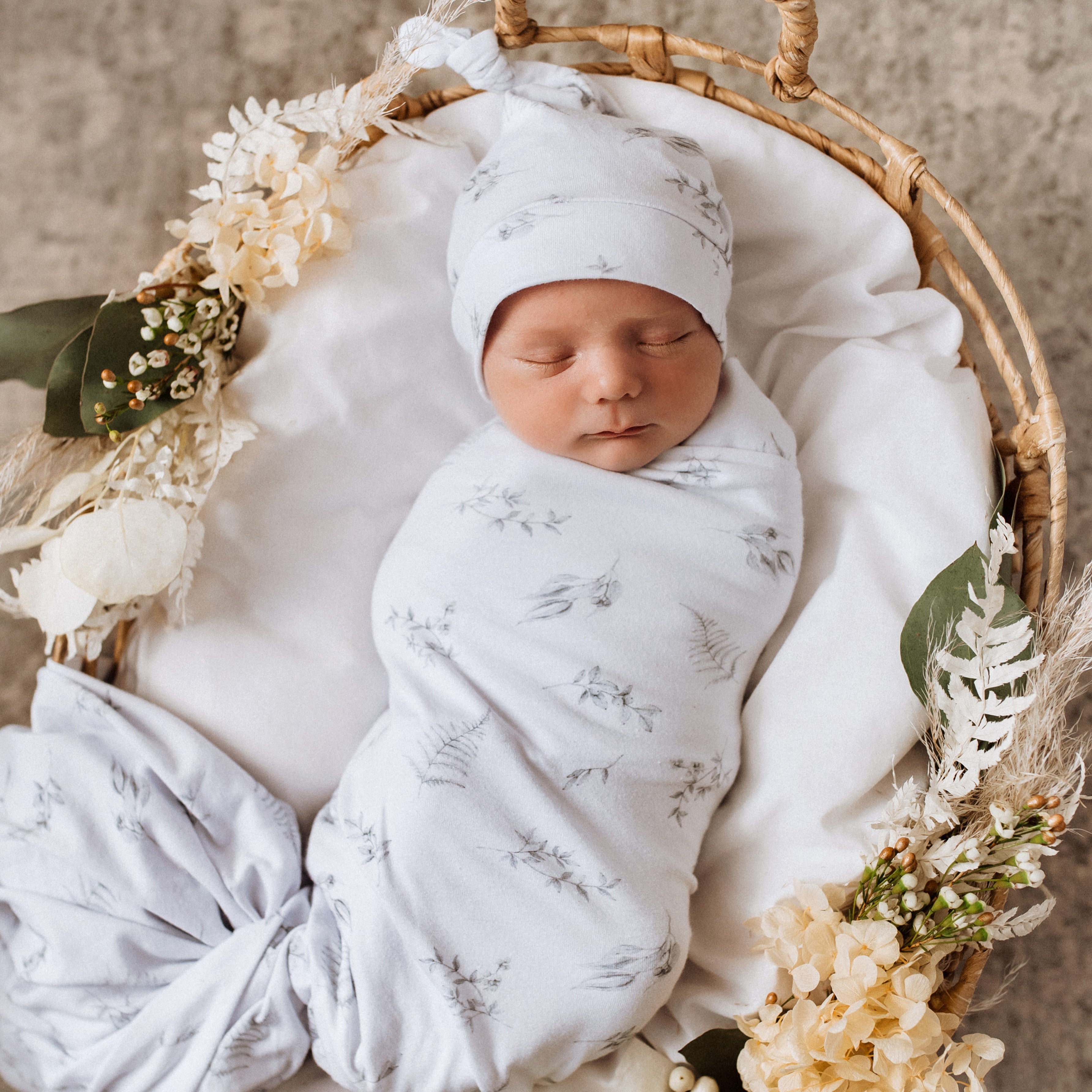 baby wrapped in jersey wrap with beanie on in bassinet