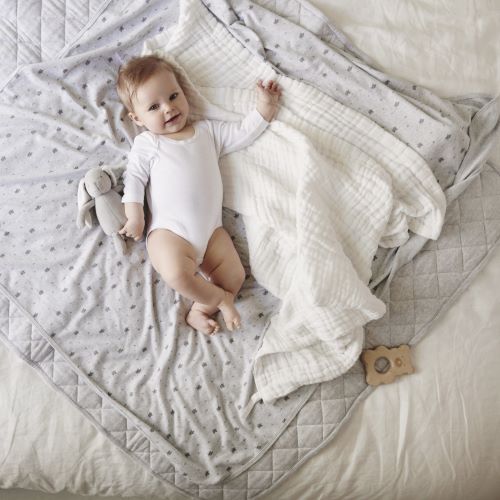 essentials white body suit on a baby laying on a white muslin and grey blanket